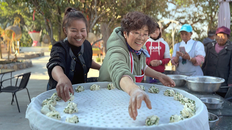 【2】旅居者趙發(fā)英（圖左二）教曼海村村民做花卷。陶思源-攝
